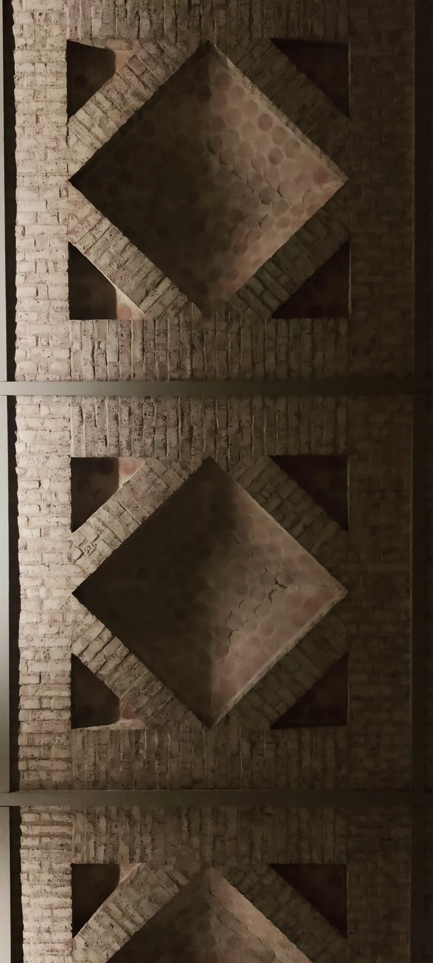 Photo en contre-plongée du plafond à caissons de la colonnade, losanges de pierre et de brique